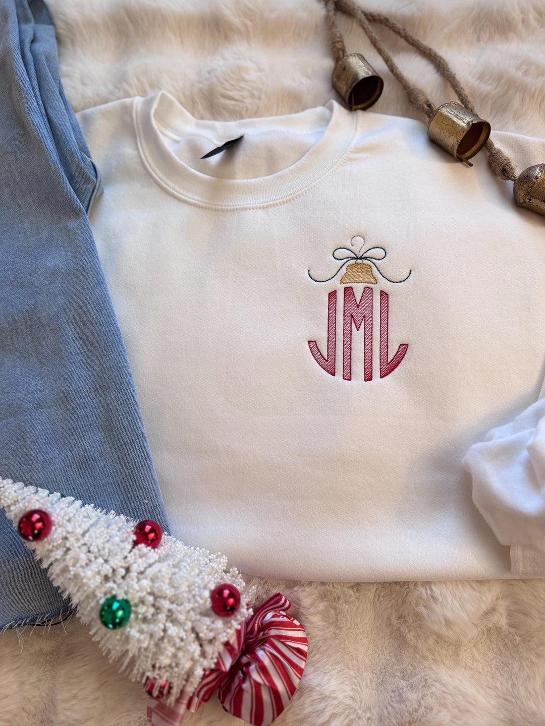 White Christmas sweatshirt featuring a red sketch stitch three-letter monogram topped with an embroidered gold ornament and delicate bow. Personalized holiday sweatshirt with custom initials.
