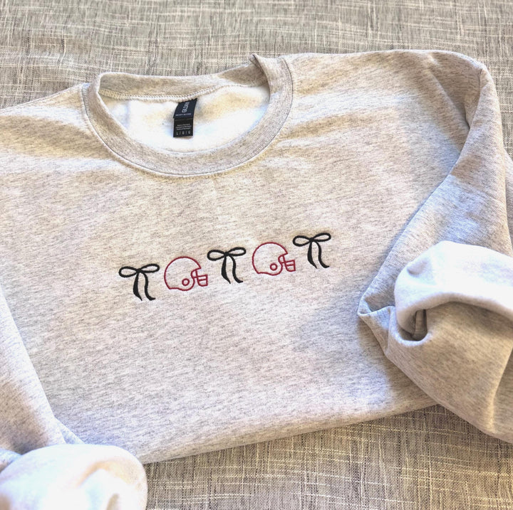 Embroidered football helmet sweatshirt with bow details in a cute coquette gameday style on a cozy crewneck