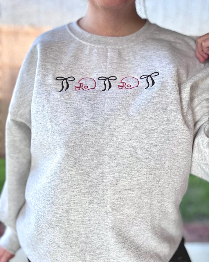 Embroidered football helmet sweatshirt with bow details in a cute coquette gameday style on a cozy crewneck