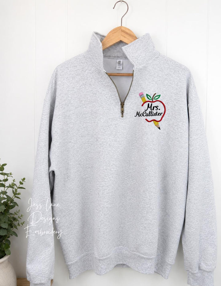 Personalized embroidered teacher apple design on a Jerzees quarter zip with a custom teacher name.