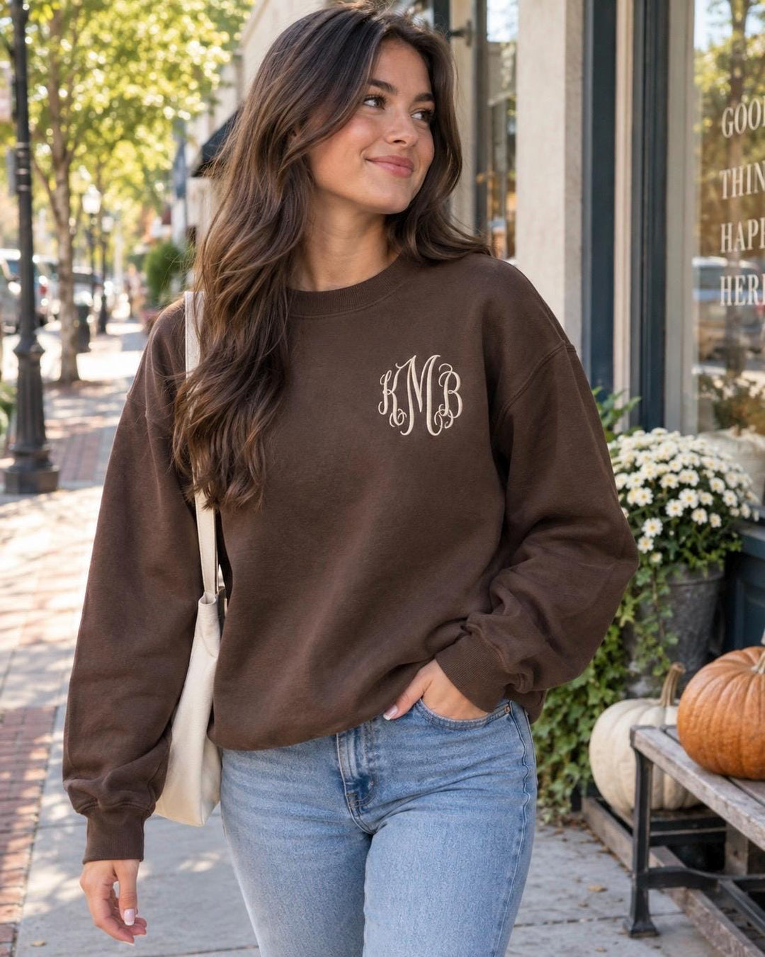 Brown monogram sweatshirt for women with cream three-letter embroidered initials, styled on a model outdoors with jeans for a casual everyday look.